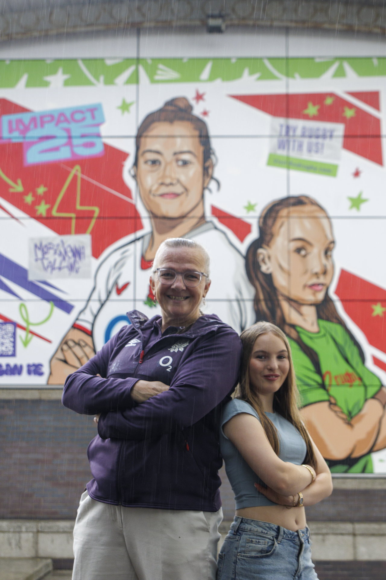 Women's RUgby World Cup winner Gill Burns back to back with local school girl Orla. You can see a colourful mural in the background featuring Red Roses player and Orla