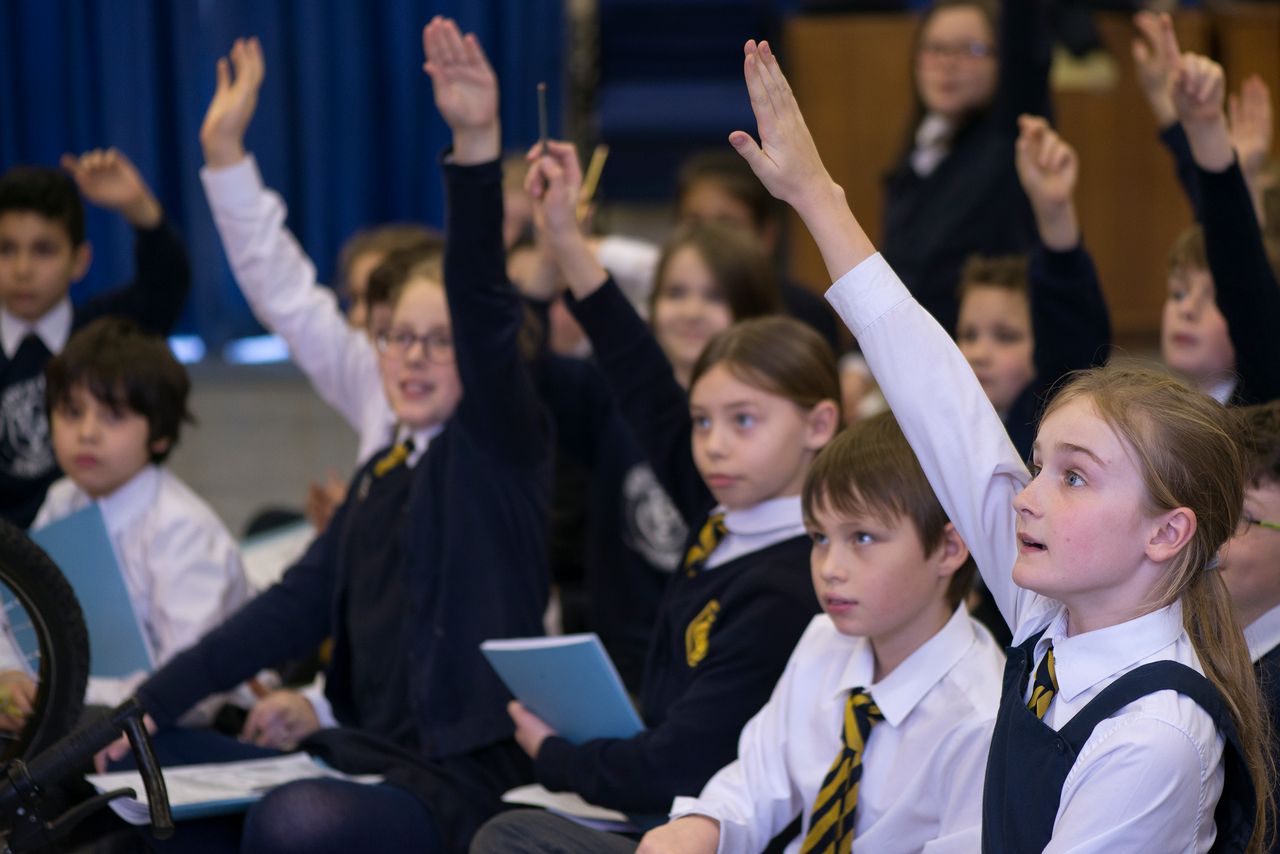 School children in a workshop with their hands up to ask questions