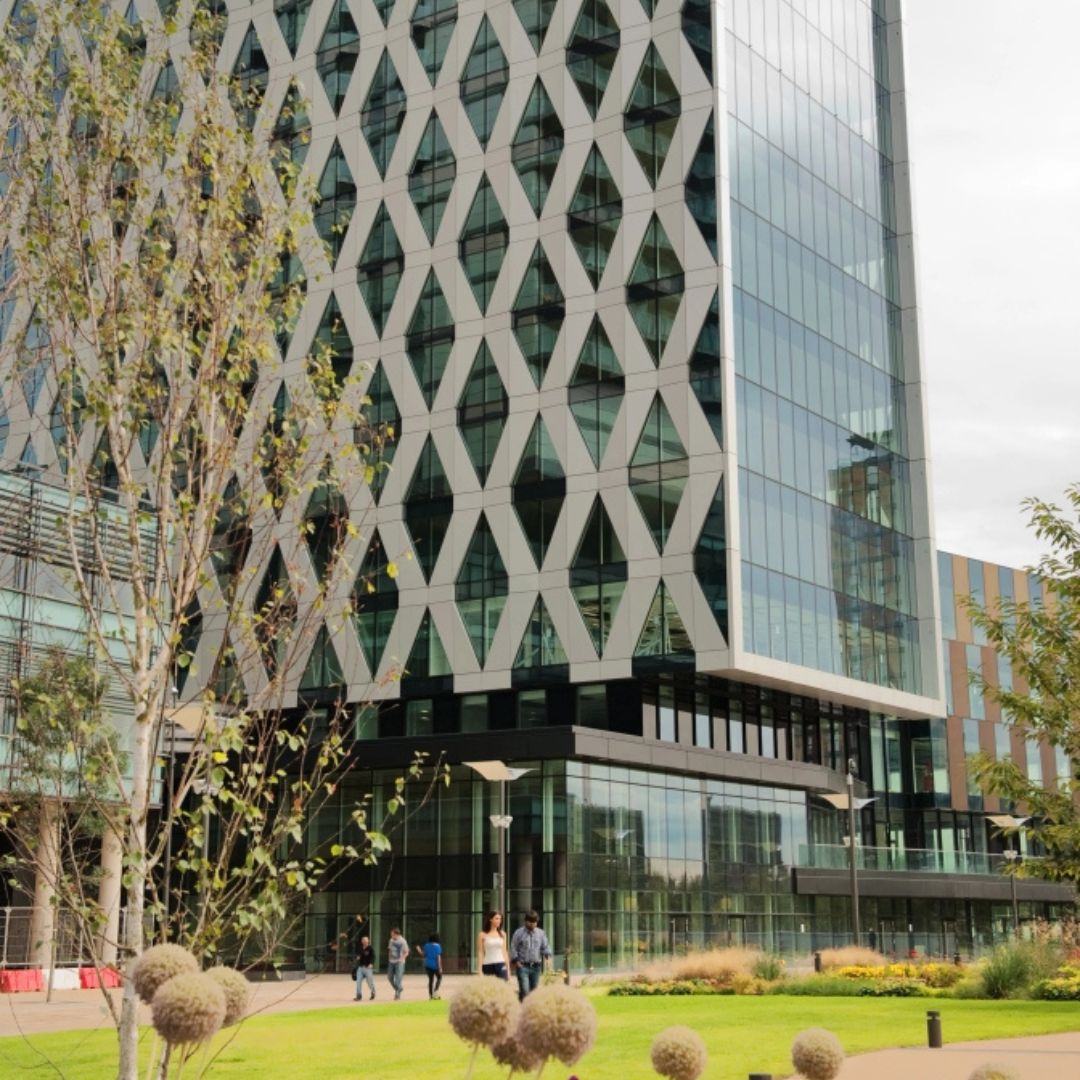 Salford University building from the outside with green grass and shrubs in front
