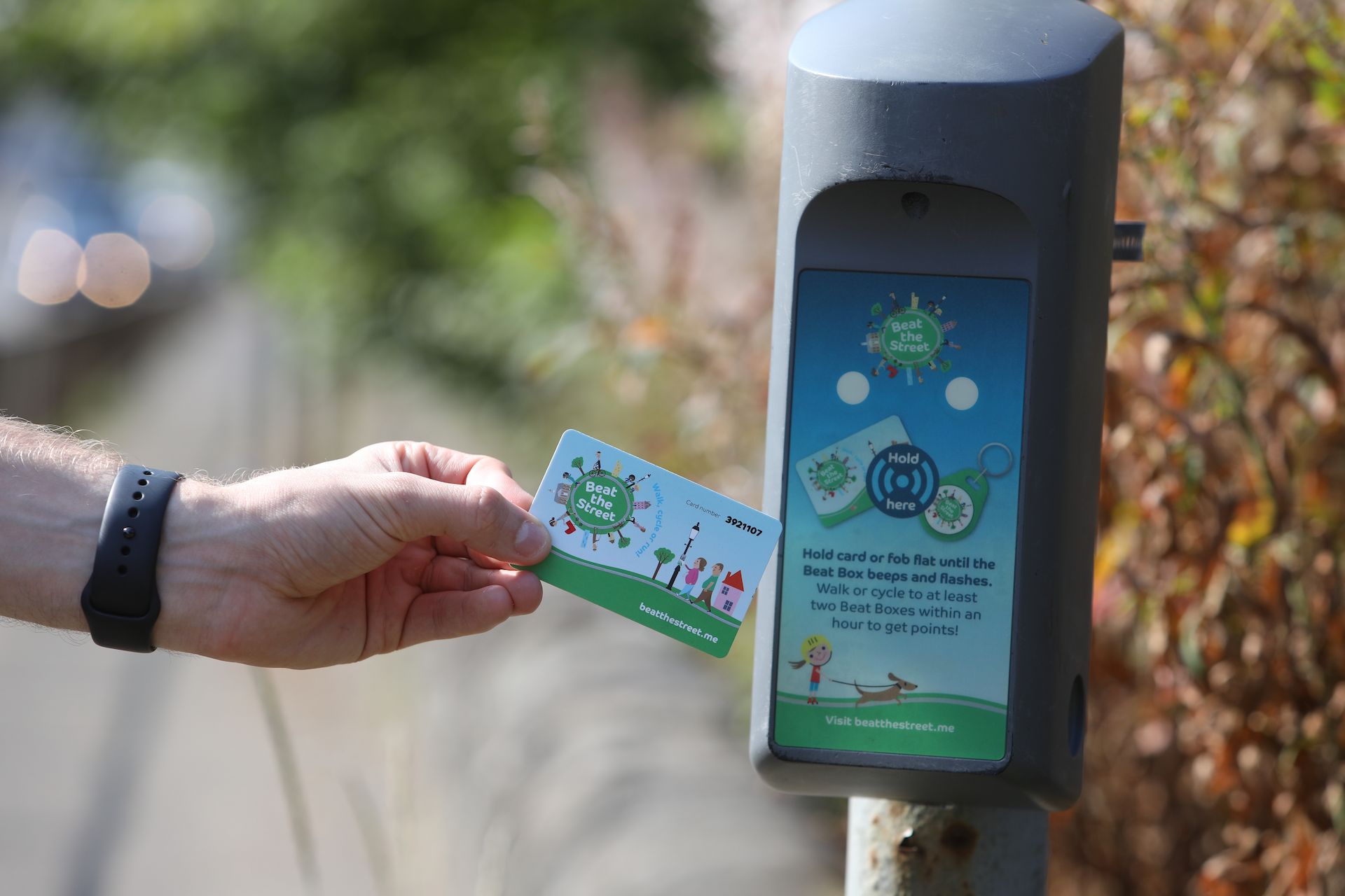 A hand holding a Salford Beat the Street game card near a beat box.