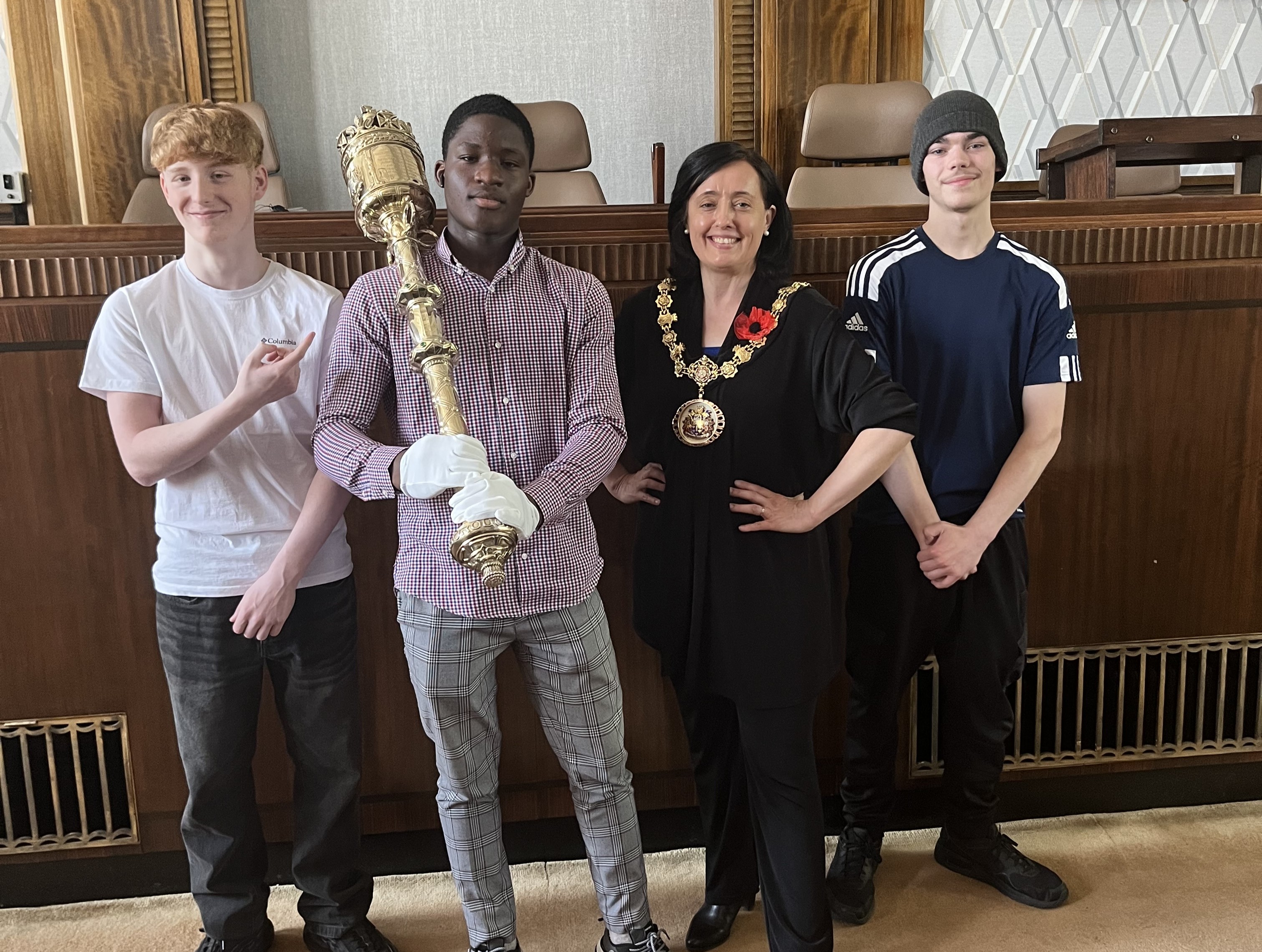 Three young people stood with the Ceremonial Mayor of Salford. One of the young people is holding a gold ornamental mace
