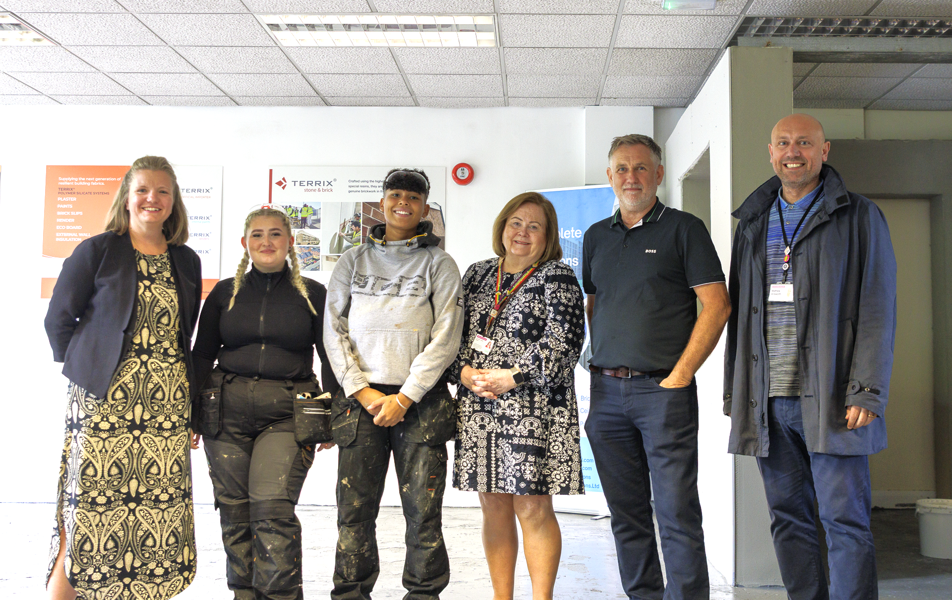 A group of people stand smiling in the Construction Skills Centre