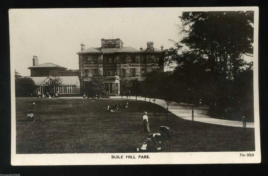 Black and white photograph of Buile Hill Mansion during the early to mid 1900's, with people gathered on the lawns and trees surrounding mansion
