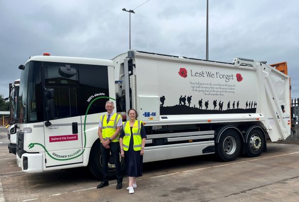People standing next to Salford City Council's first electric bin wagon with the Lest We Forget message on the sides of the wagon