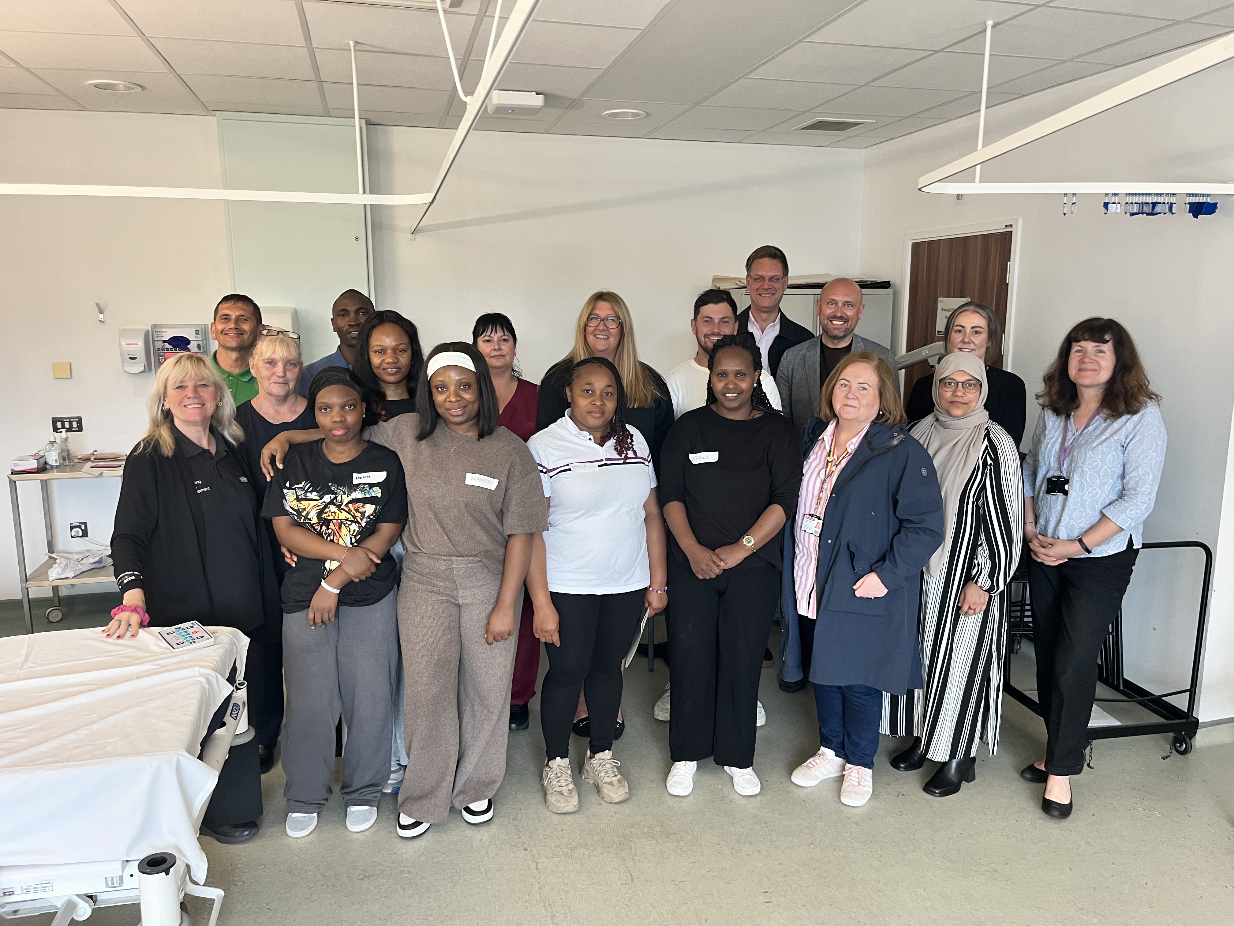 A group of people stand smiling in a ward setting