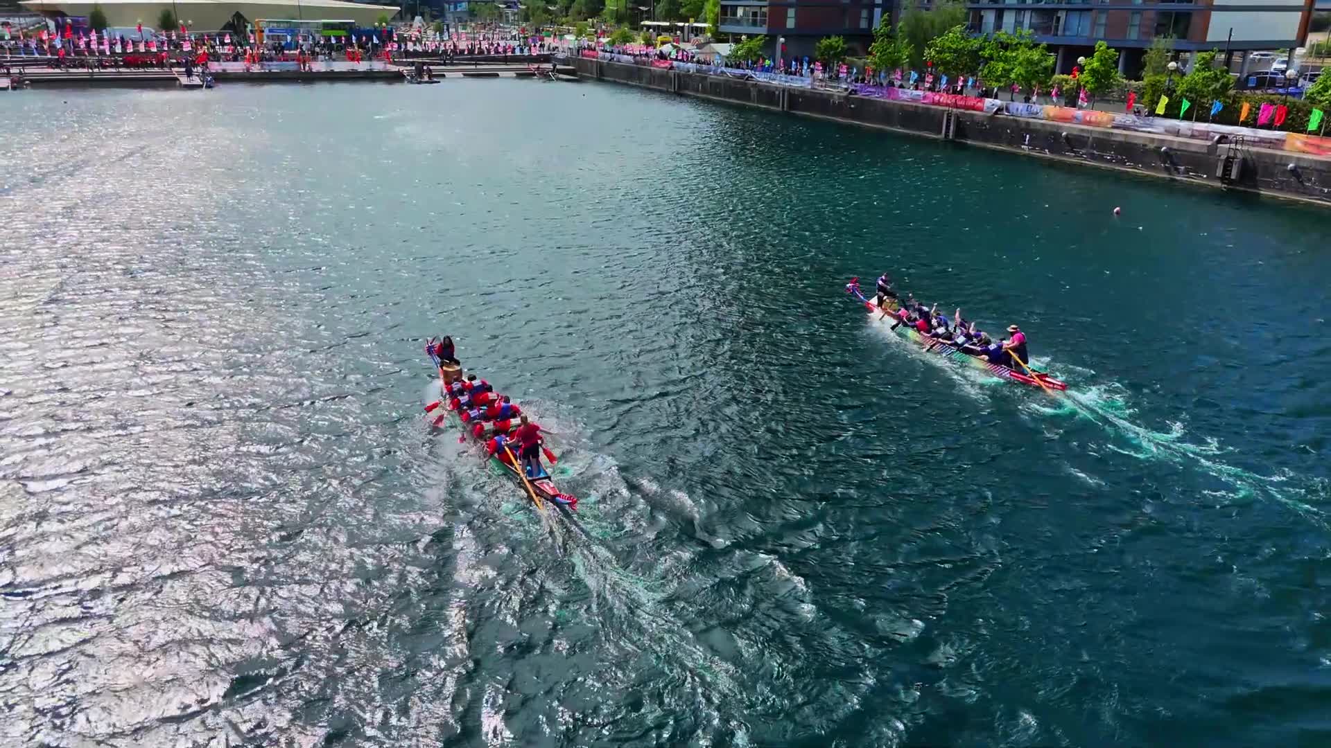 Two dragon boats racing across Salford Quays