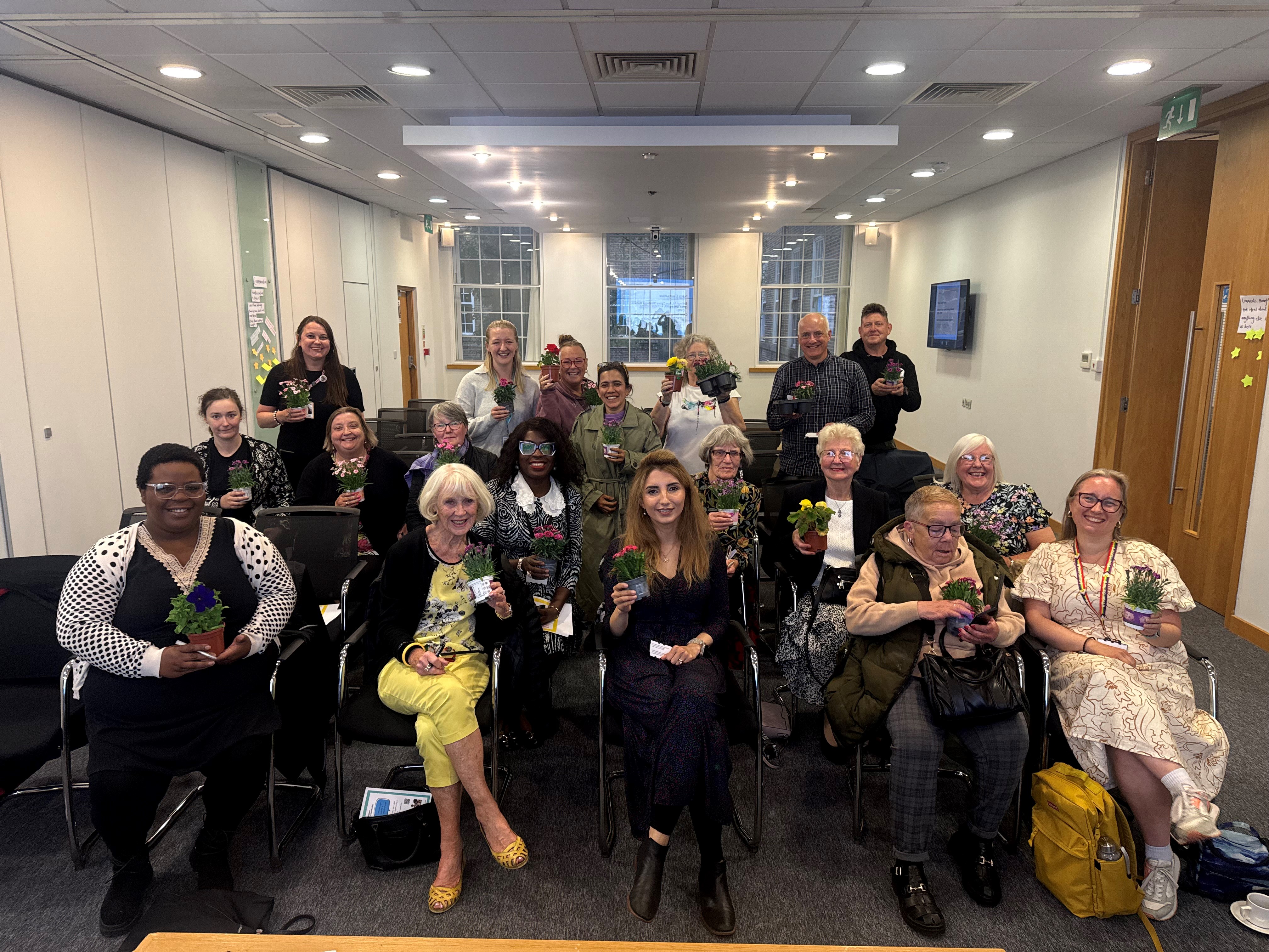 An image of a group of attendees, councillors and community representatives at a Carers Week celebration event hosted at Salford Civic Centre