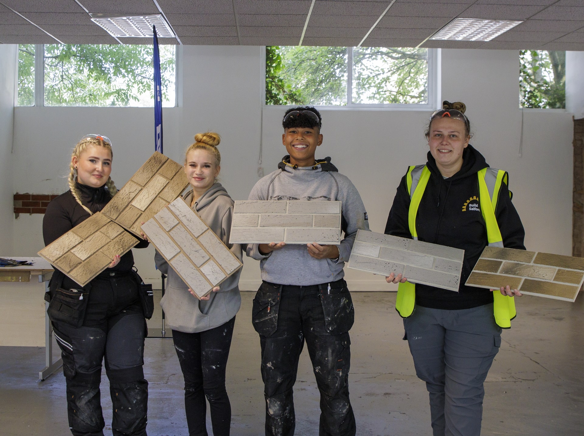 Four women stand posing with brickslip samples